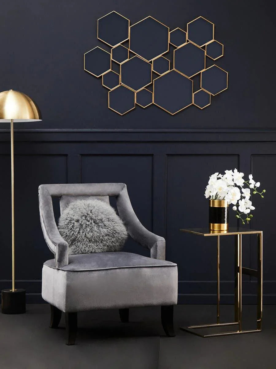 Grey velvet accent chair with fluffy cushion, gold lamp, and side table in modern living room