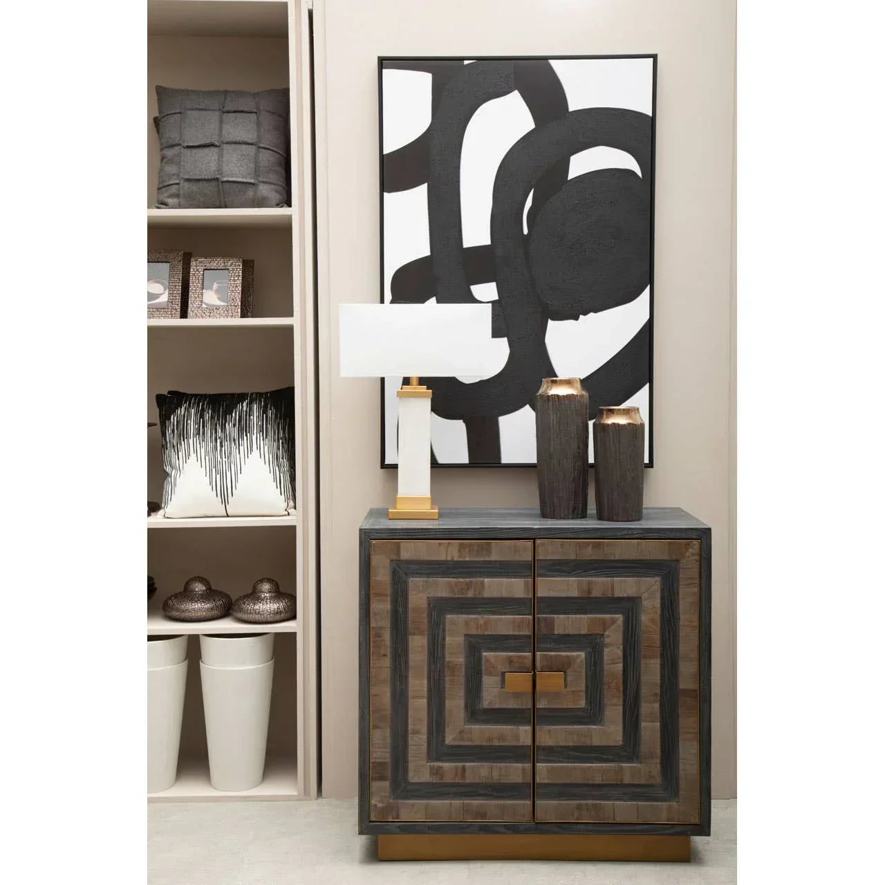 Geometric wood sideboard cabinet with gold base, table lamp, and vases in a modern hallway