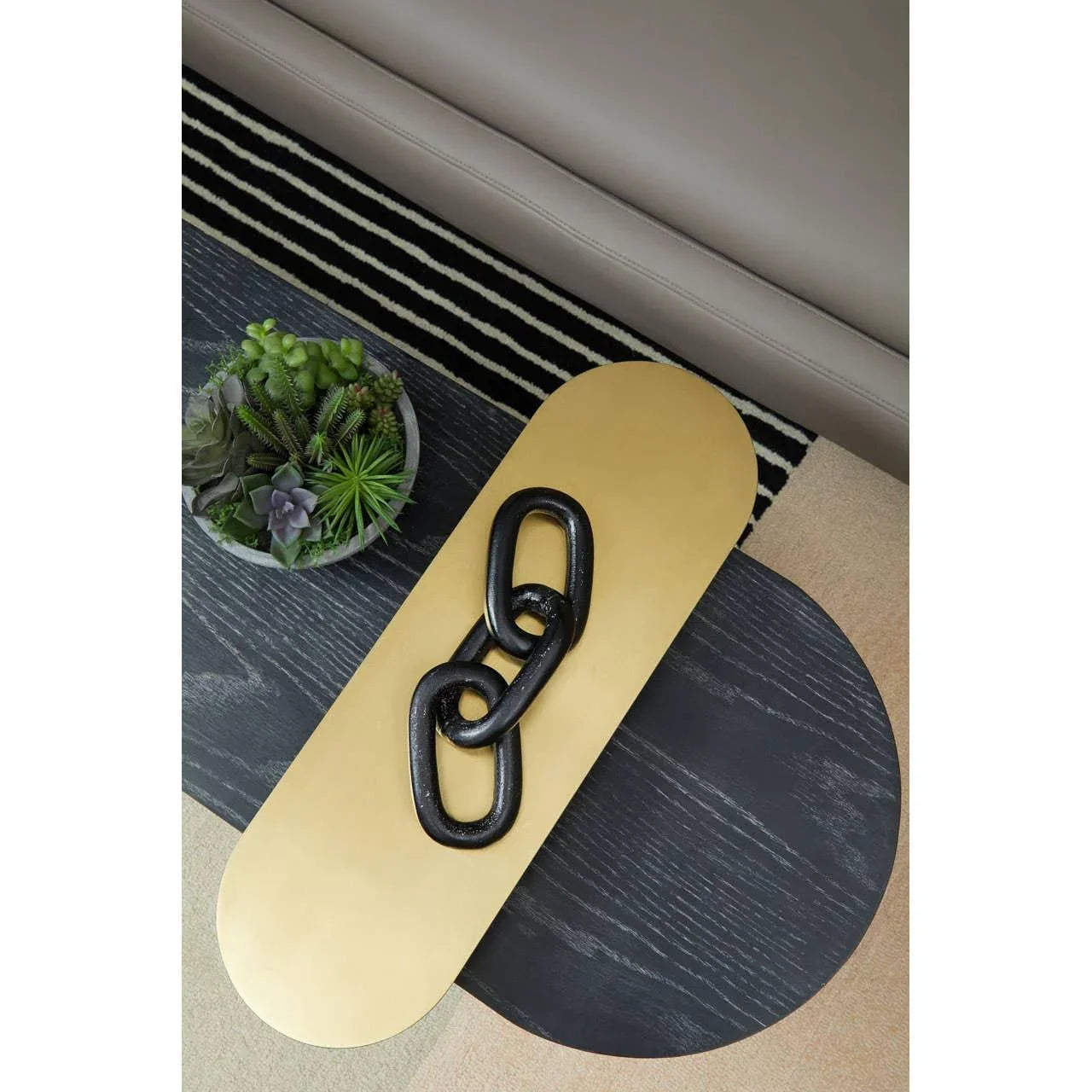 Modern coffee table with black wood and gold accents, decorative chain and succulent bowl