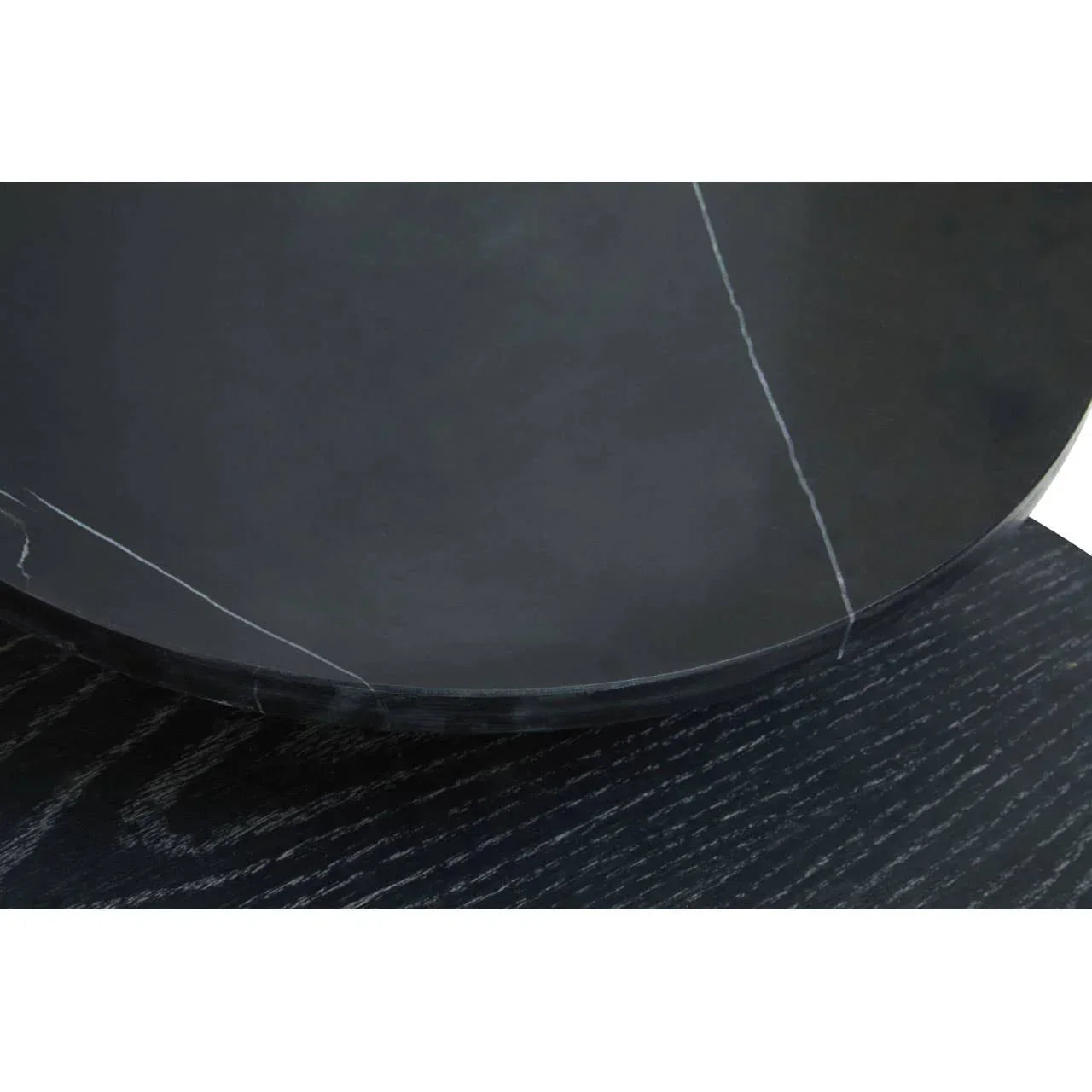 Black marble table top with white veining and dark wood grain base close-up
