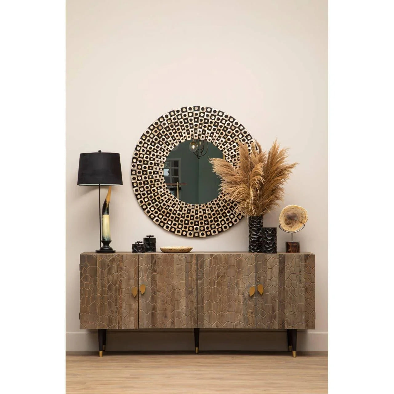 Wooden sideboard with gold handles, circular mirror, and decorative table lamp
