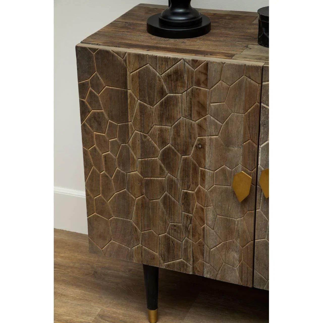 Carved wood sideboard with textured geometric doors and black legs with gold tips