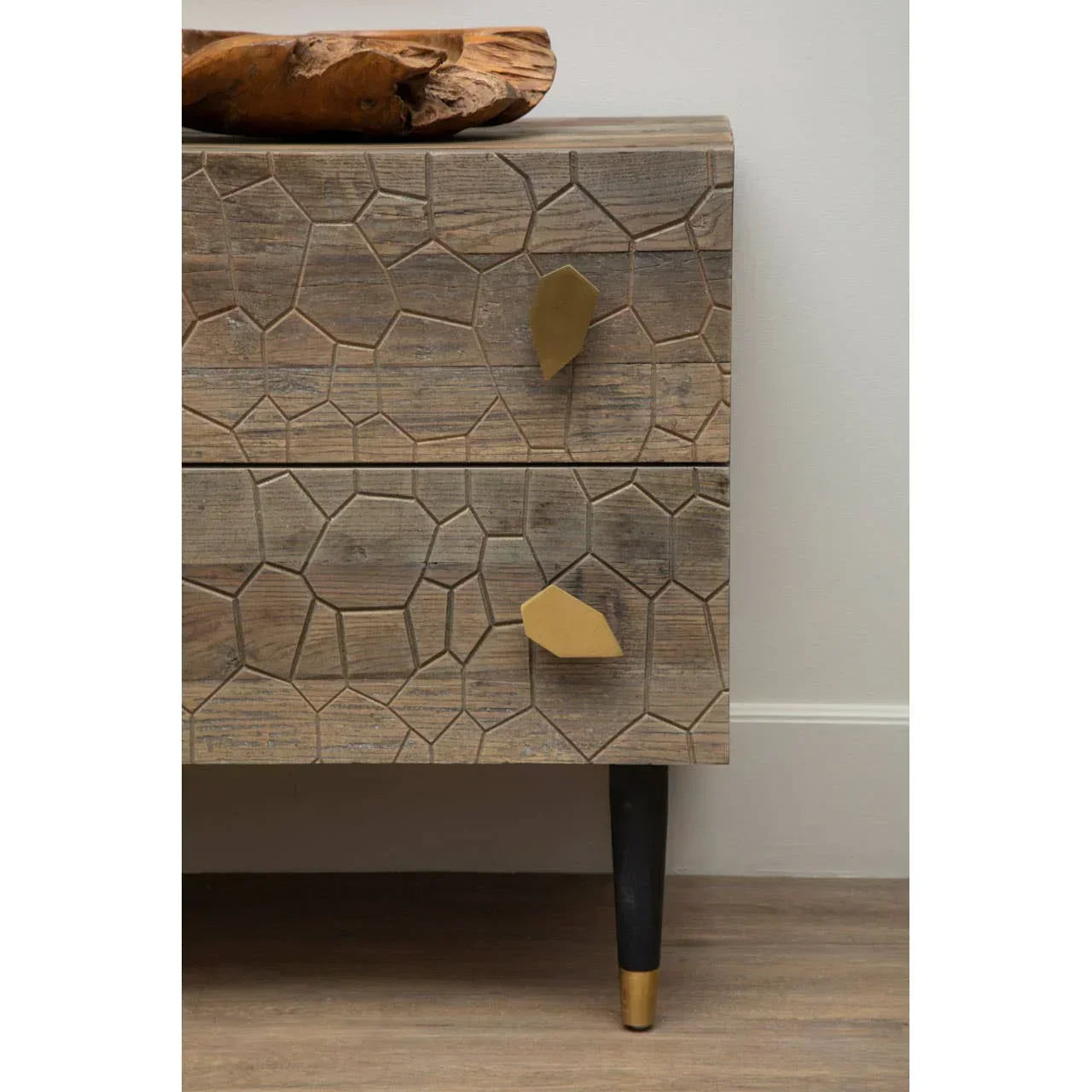 Wooden chest of drawers with geometric carved front and gold handles on black tapered legs