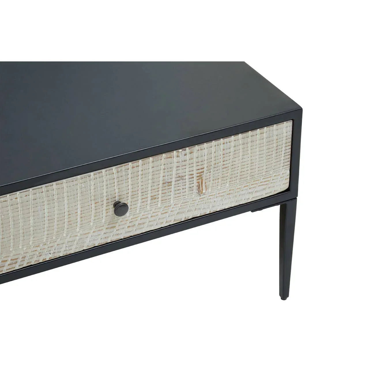 Black side table with rattan drawer front and slim tapered legs, close-up angle