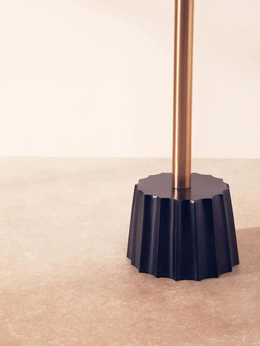 Black fluted lamp base with brushed gold metal stem on neutral surface