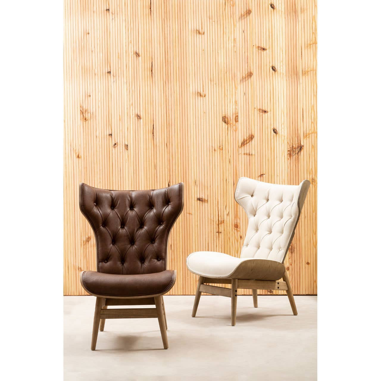Brown leather effect chair featuring a winged back design and tufted upholstery, set against a textured wooden backdrop.