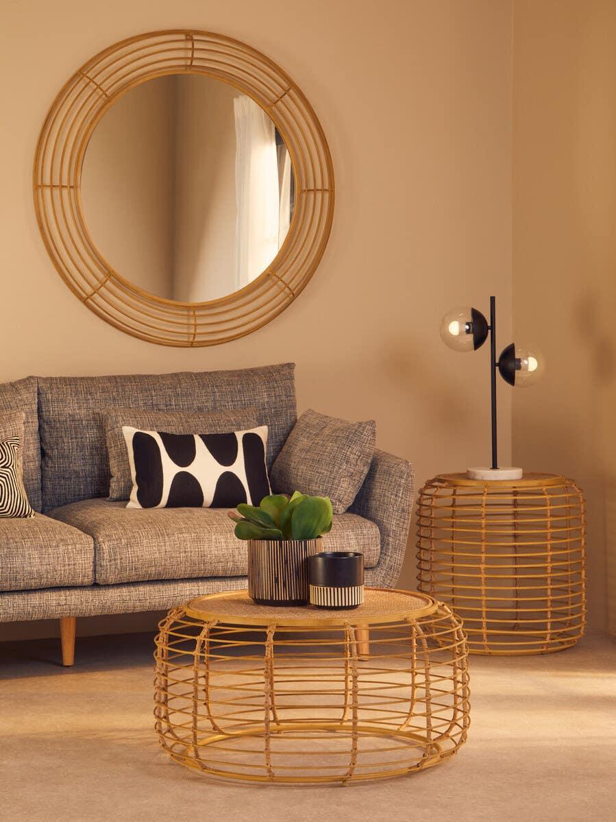 Grey fabric sofa with monochrome cushion, rattan coffee table, round mirror, modern lamp