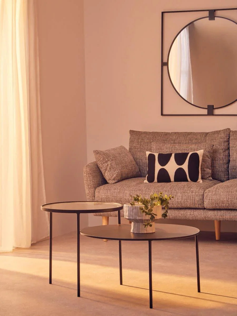 Grey fabric sofa with monochrome cushion, two black coffee tables, round wall mirror