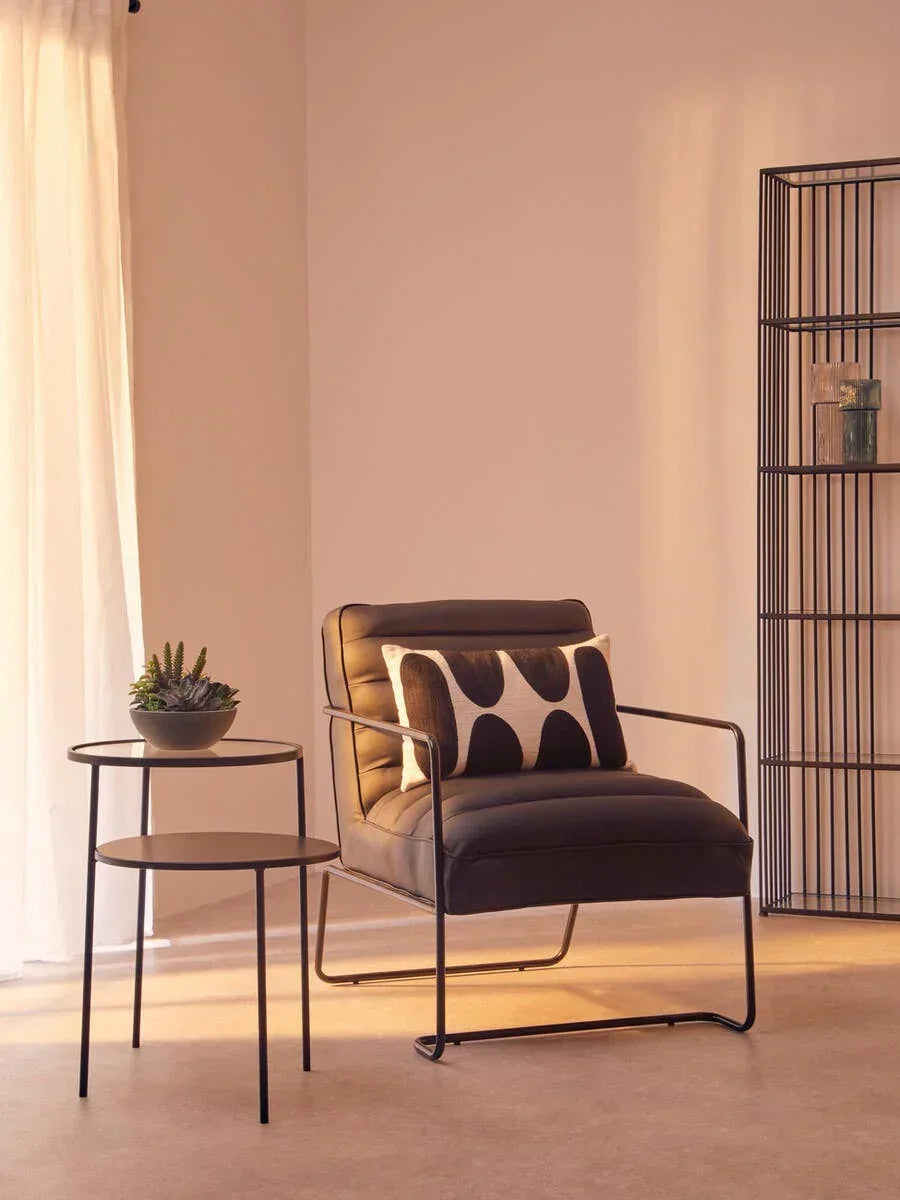 Black accent chair with metal frame beside round side table in modern living room
