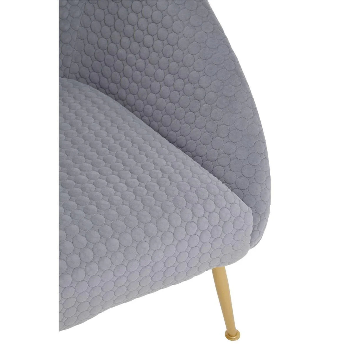 Close-up of grey fabric armchair with quilted circular pattern and gold metal leg