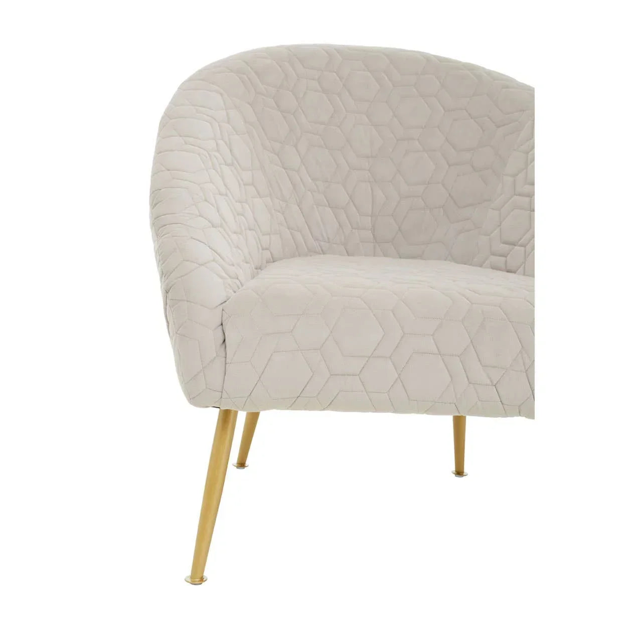 Beige accent chair with hexagonal quilted upholstery and gold metal legs, angled side view