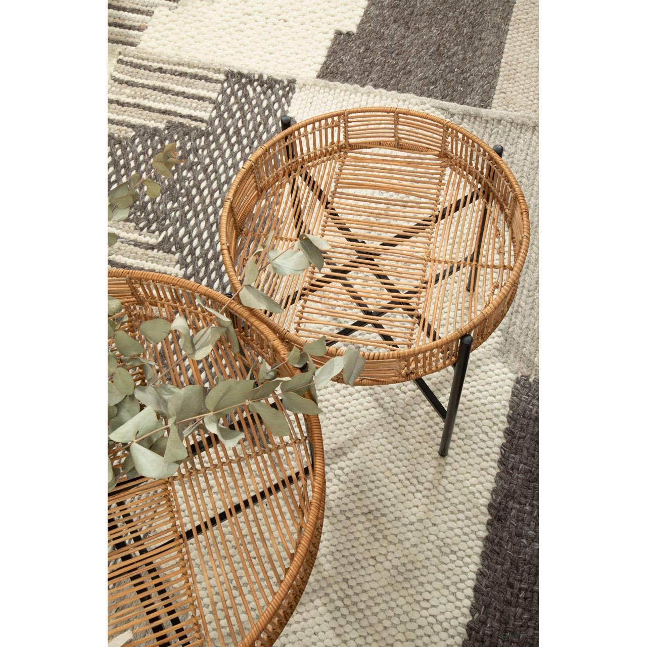 Round rattan side tables with black legs on geometric textured rug