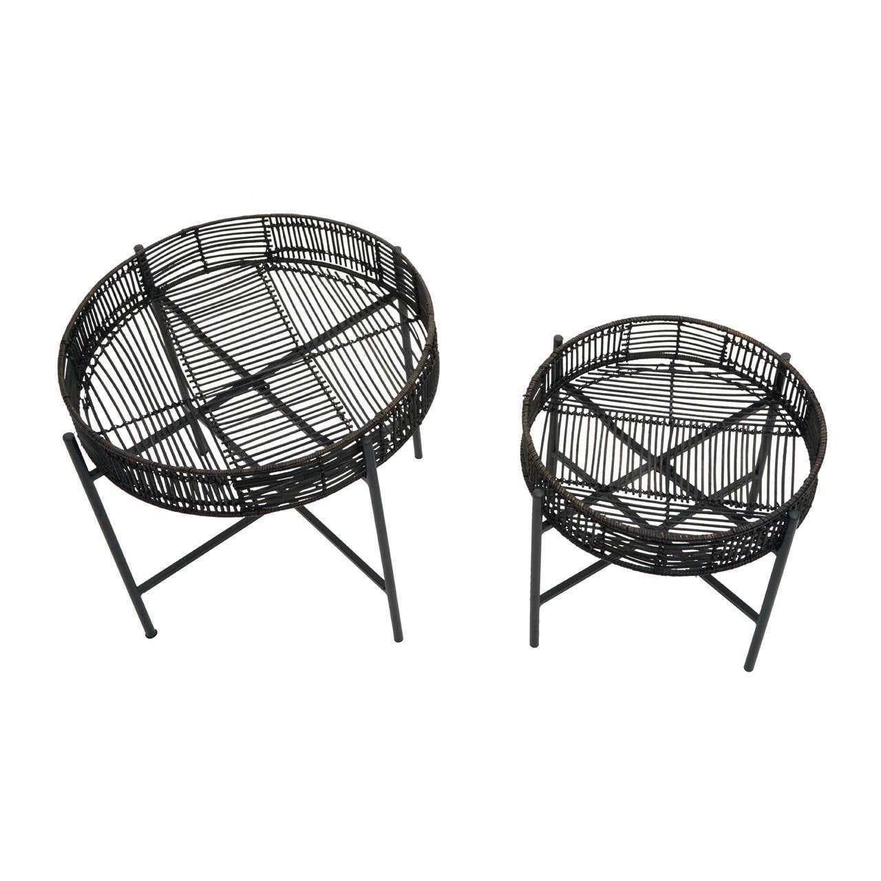 Set of two round black rattan side tables with metal legs on white background