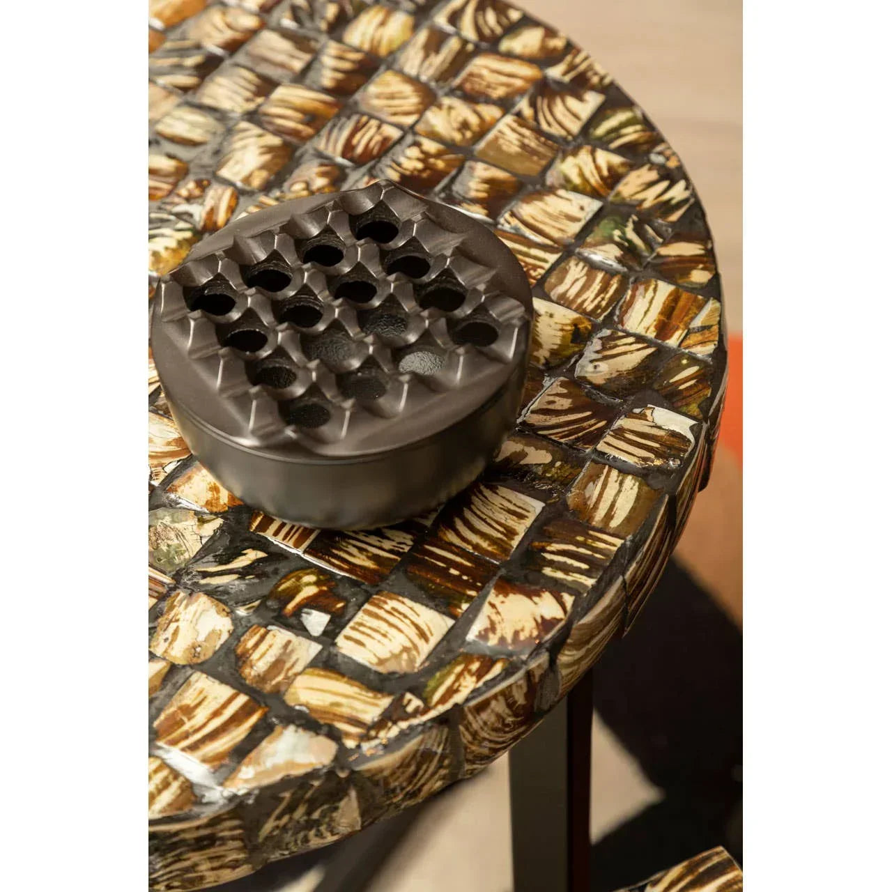 Round accent table with mosaic shell inlay top and dark metallic decor piece