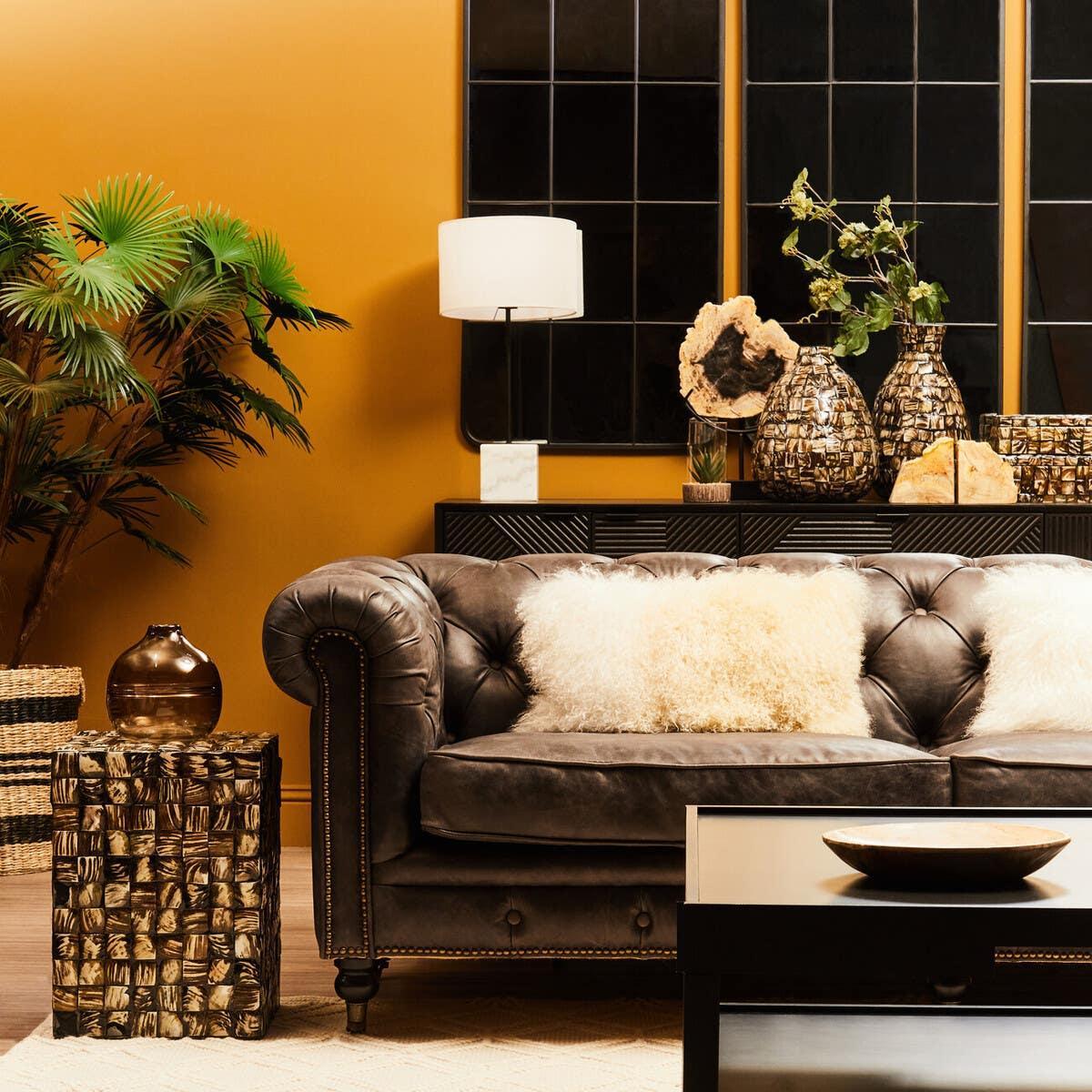 Brown leather sofa with cream cushions in modern living room with gold decor accents