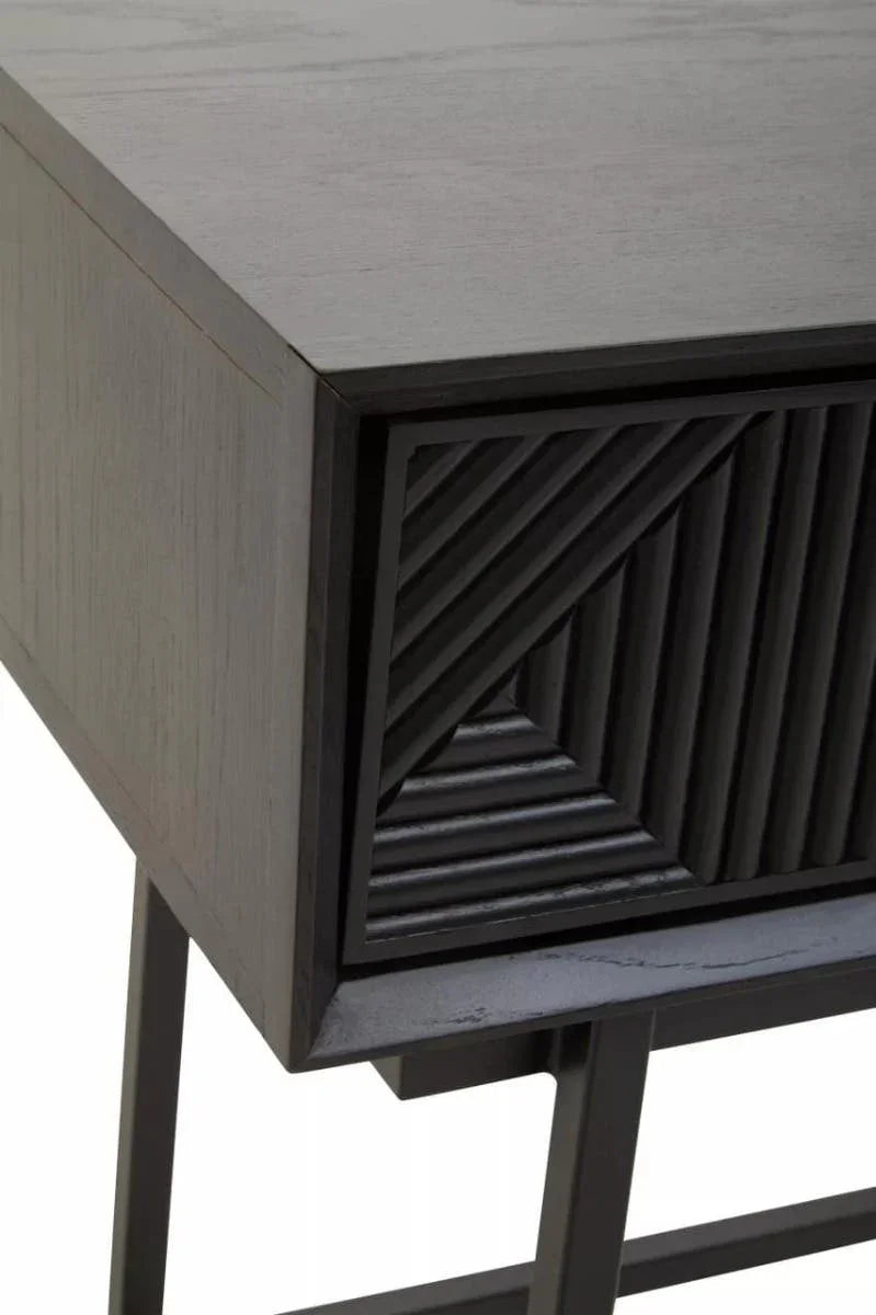 Black wooden side table with textured geometric drawer and metal legs, close-up angle