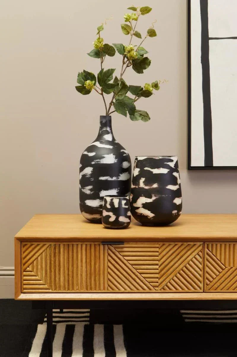Patterned black and white vases on a wooden sideboard with geometric front panels