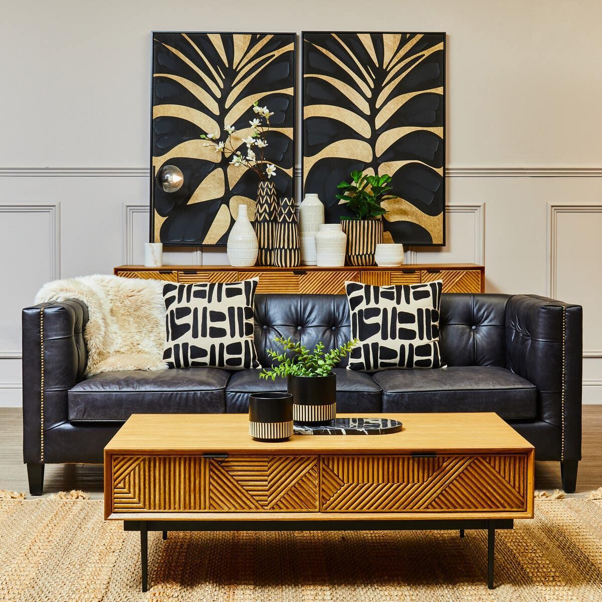 Black leather sofa with patterned cushions, wooden coffee table and sideboard, modern decor