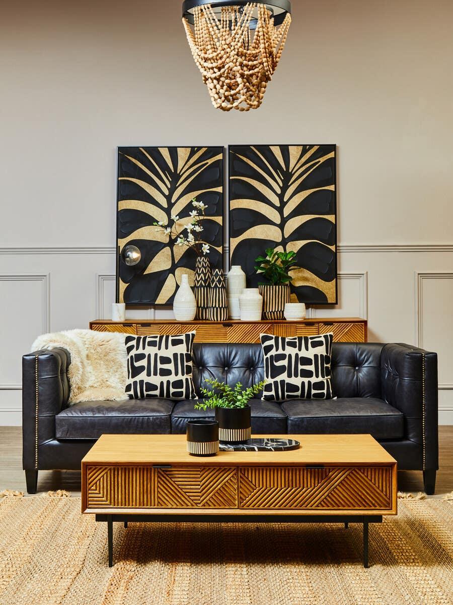 Black leather sofa with patterned cushions and wooden coffee table in modern living room