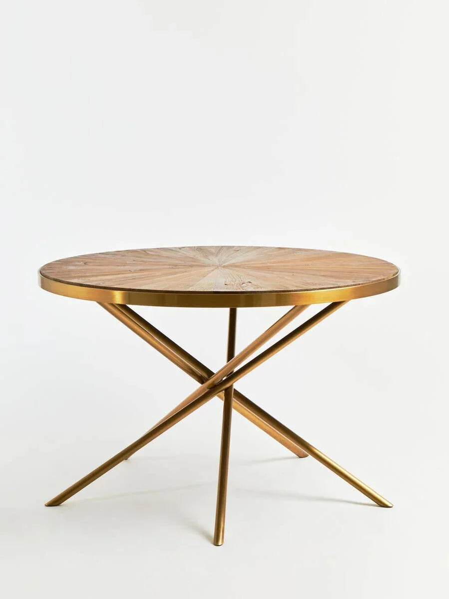 Round dining table with wood top and gold metal crossed legs on white background