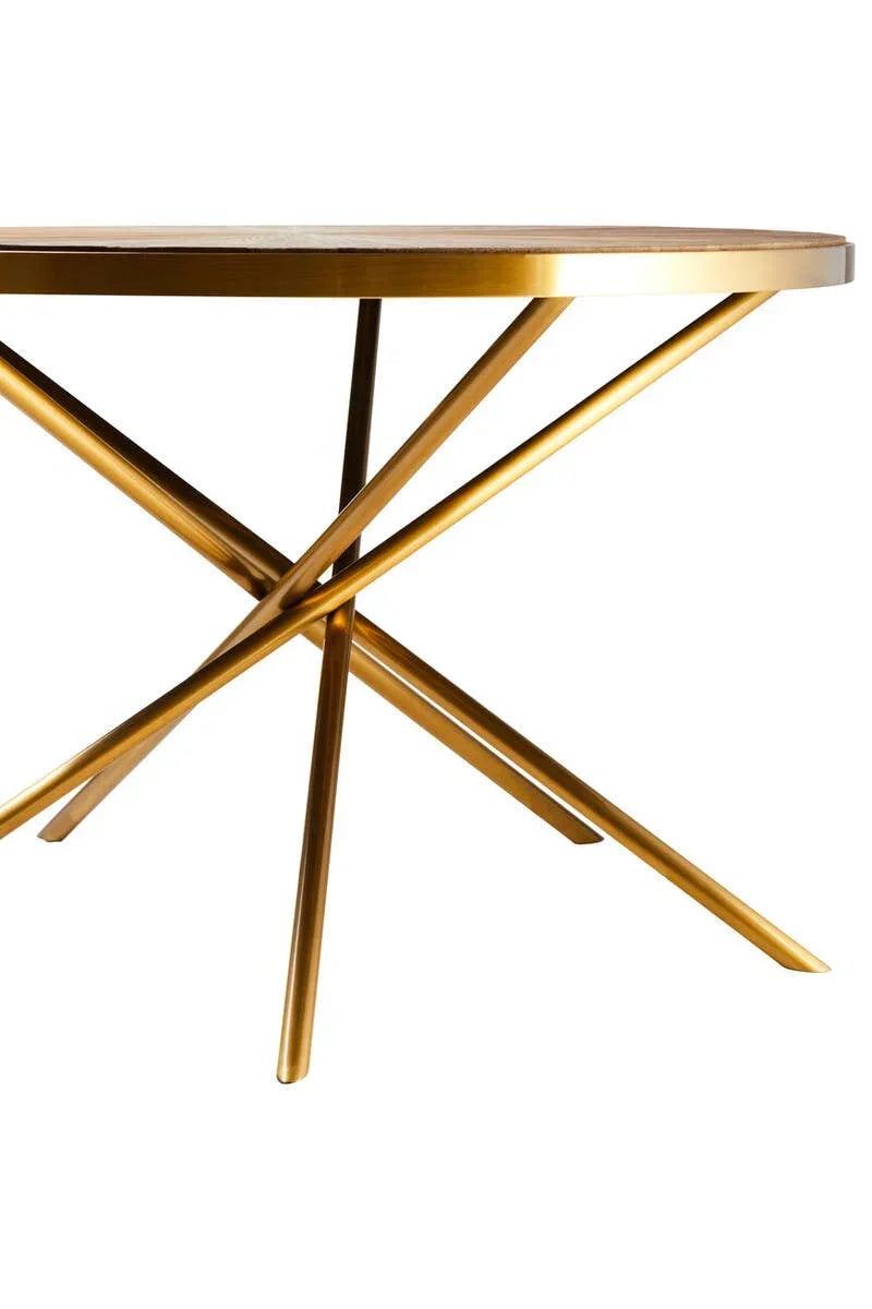 Gold metal dining table with round wooden top and intersecting legs, side angle view