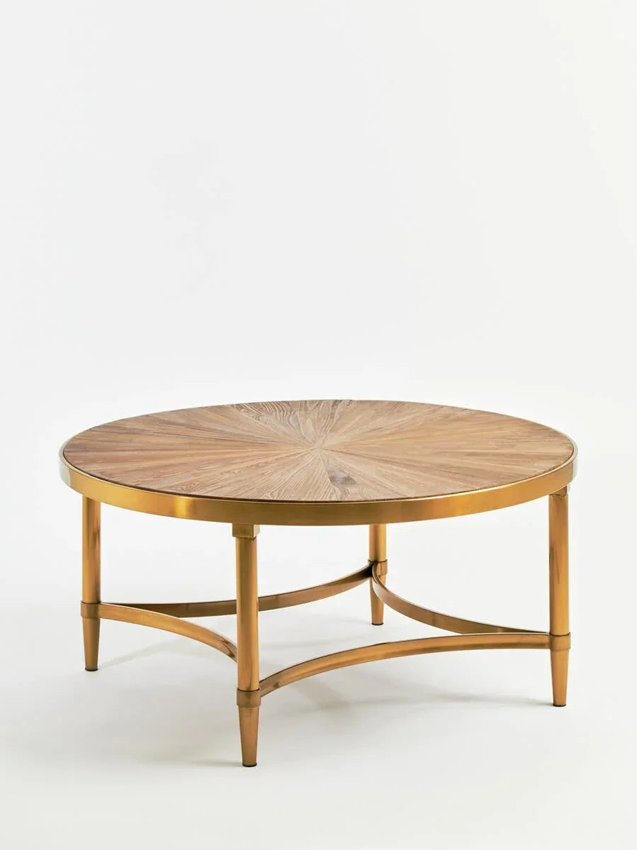 Round wooden coffee table with gold metal legs and starburst pattern top on white background