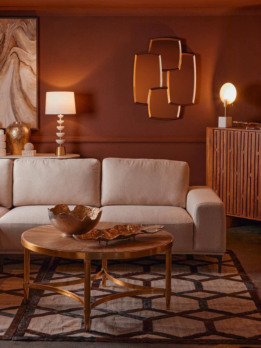 Modern beige fabric sofa with gold round coffee table in a contemporary living room setting