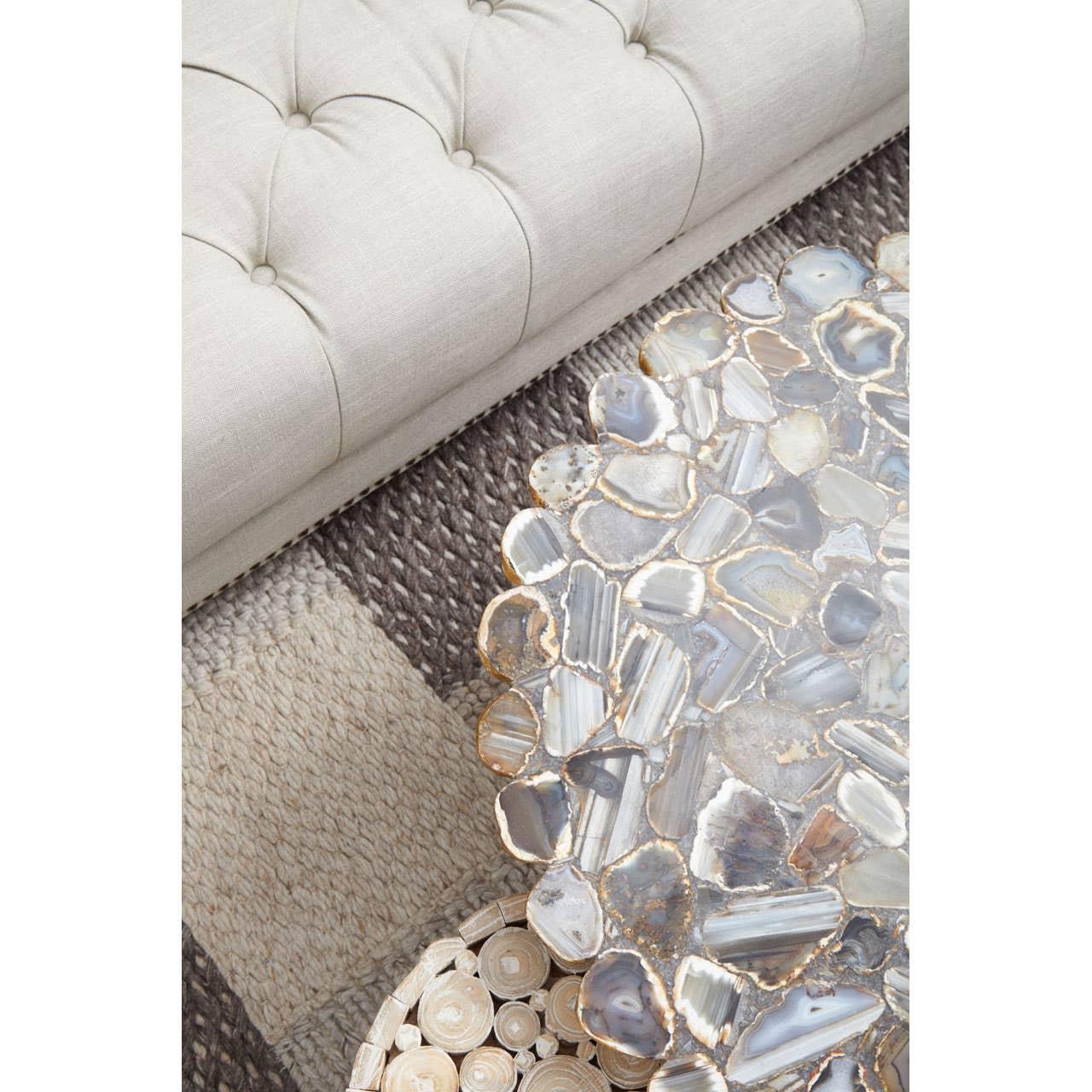 Agate coffee table with gold trim beside tufted beige sofa and textured woven rug