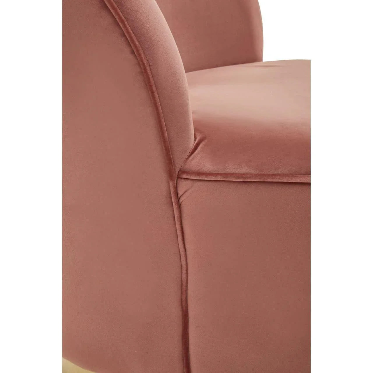 Close-up of pink velvet armchair upholstery with curved armrest and seat detail
