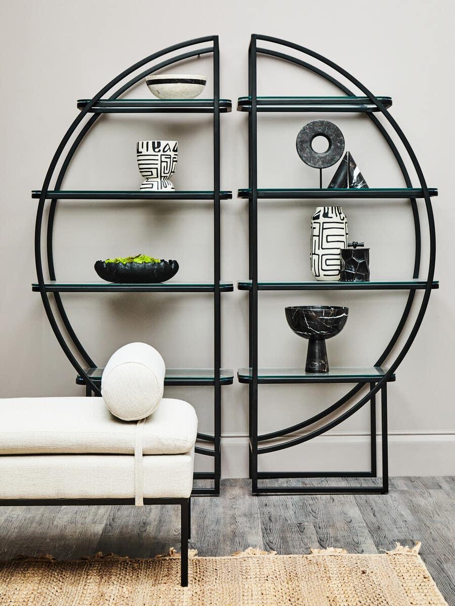 Black metal and glass shelving unit with geometric decor beside modern cream bench