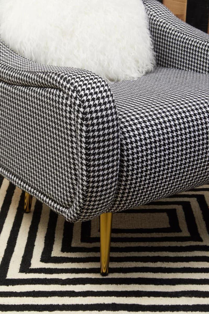 Houndstooth armchair with gold legs and white cushion on geometric black and white rug