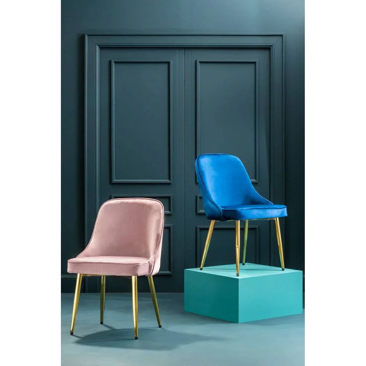 Velvet dining chairs with gold legs in pink and blue, set against a dark paneled wall