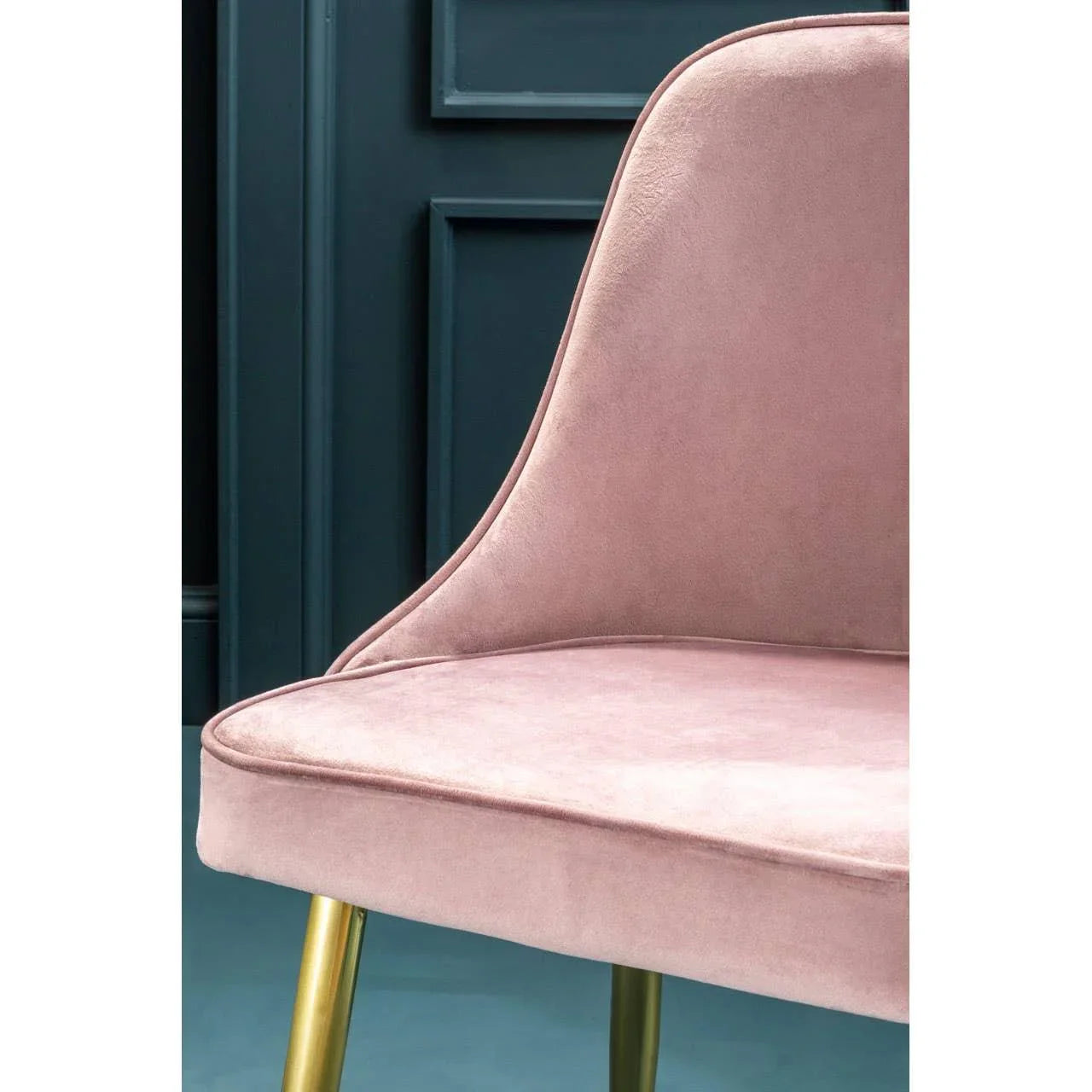 Blush pink velvet dining chair with gold legs against dark panelled wall