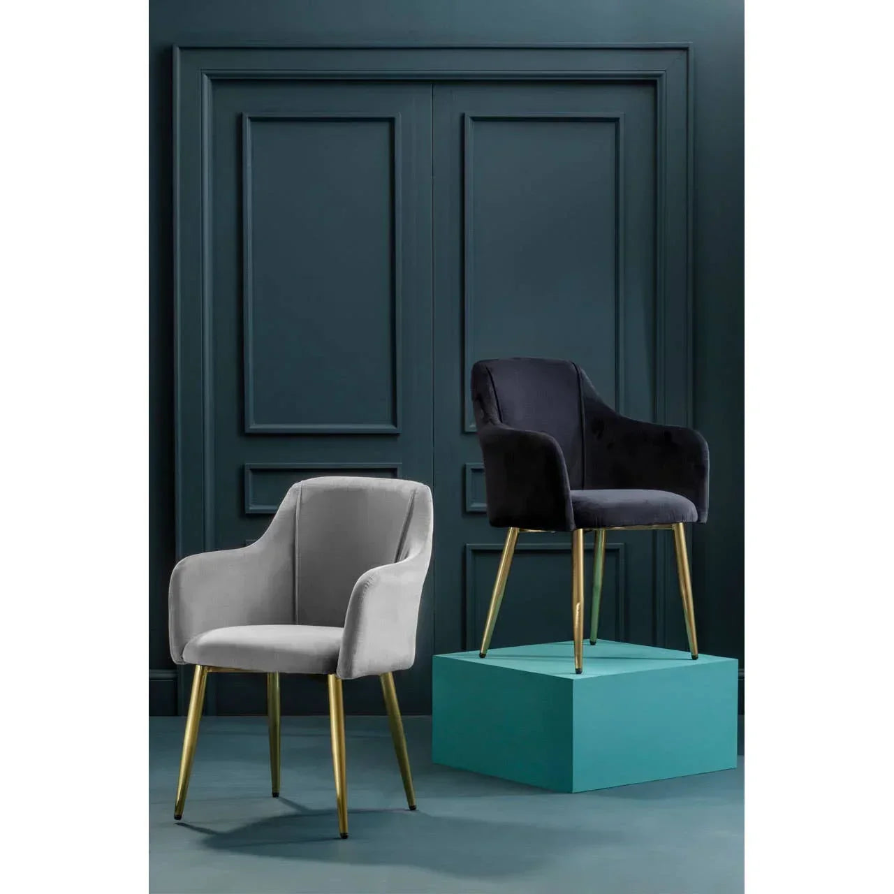 Velvet accent chairs with gold legs, one in grey and one in black, against a teal wall
