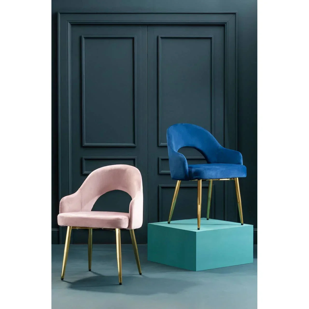 Pink and blue velvet accent chairs with gold legs against dark panel wall