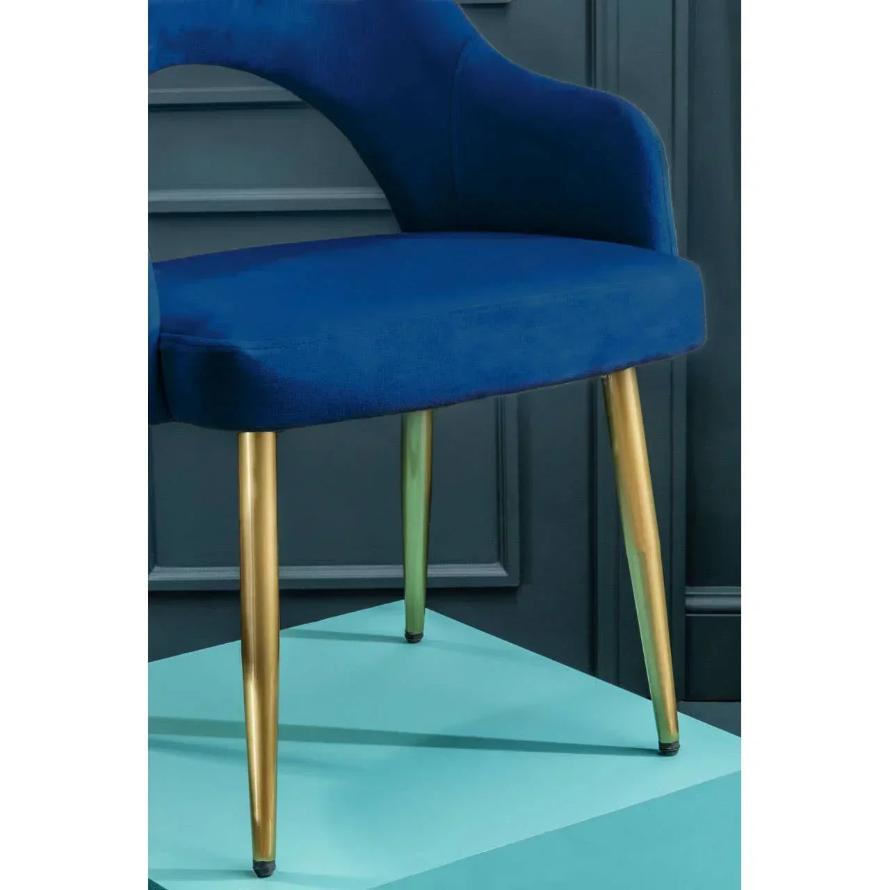 Blue velvet dining chair with gold metal legs against paneled wall
