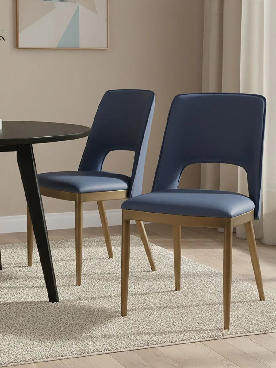 Navy upholstered dining chairs with gold legs beside round black dining table