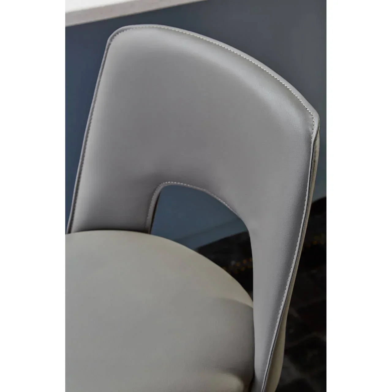 Grey faux leather dining chair with curved backrest and cut-out detail close up