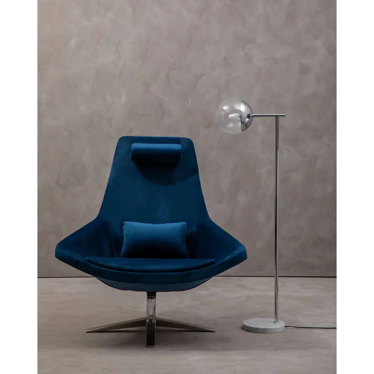 Blue velvet accent chair with cushion and headrest beside modern chrome floor lamp