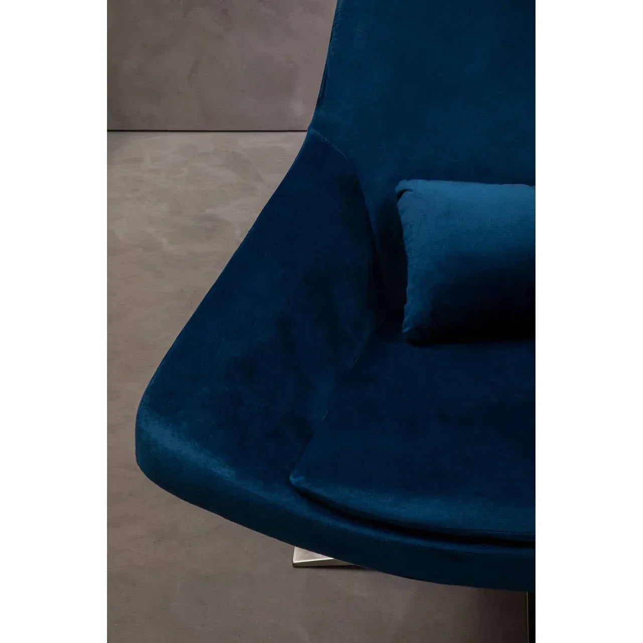 Close-up of blue velvet accent chair with cushion on modern grey floor