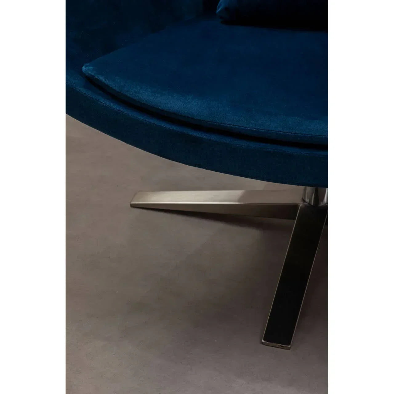 Blue velvet chair cushion with chrome swivel base on grey floor