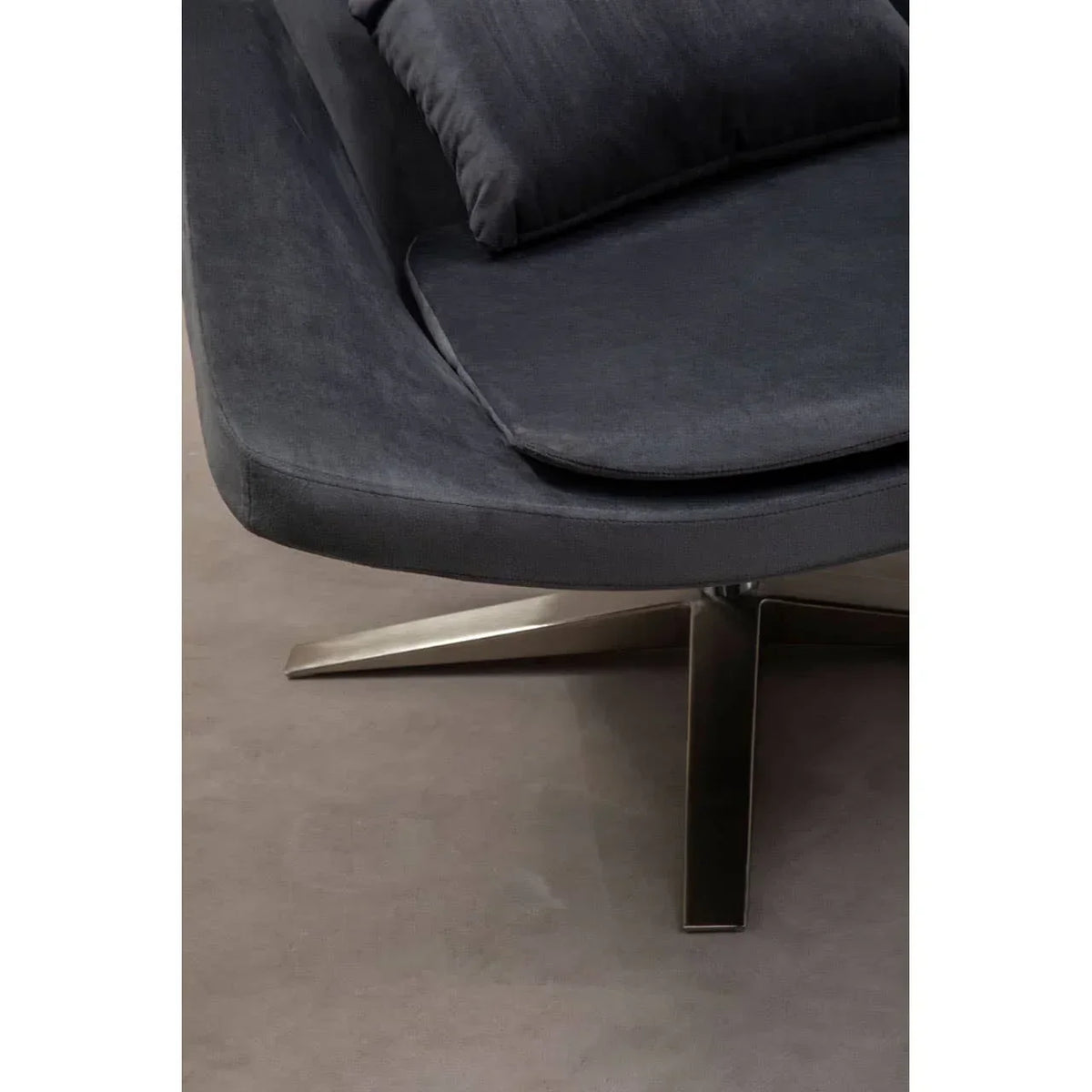 Close view of dark upholstered swivel chair seat and metal base on light floor
