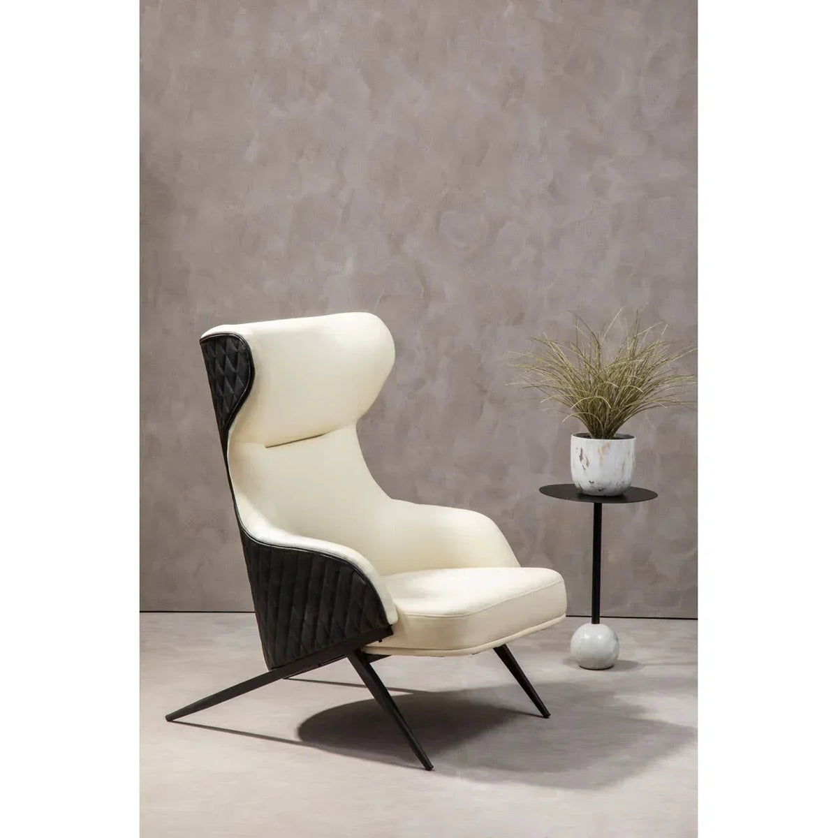 Modern accent chair with cream upholstery and black quilted sides beside round side table