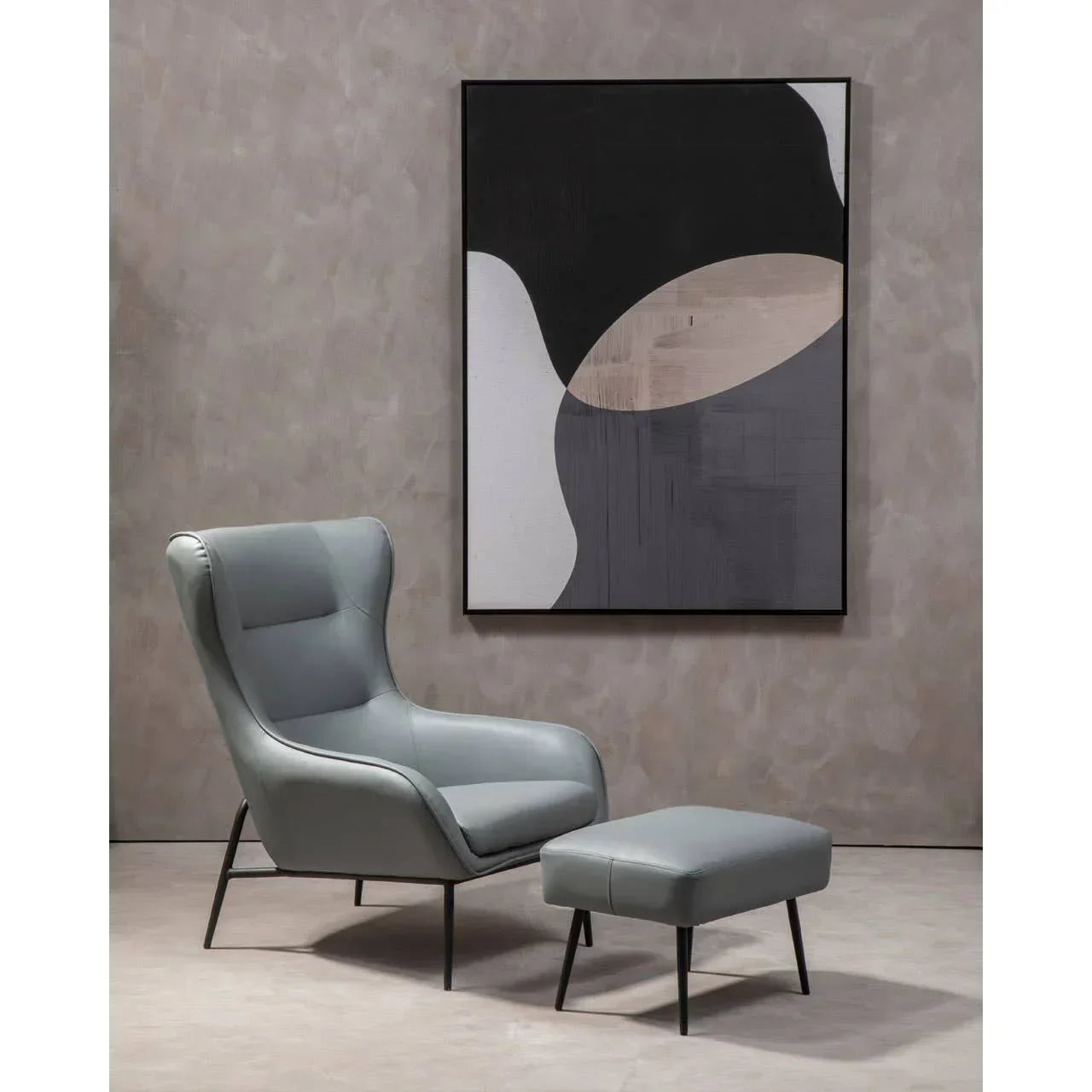 Grey leather armchair with matching ottoman and abstract wall art in modern living room