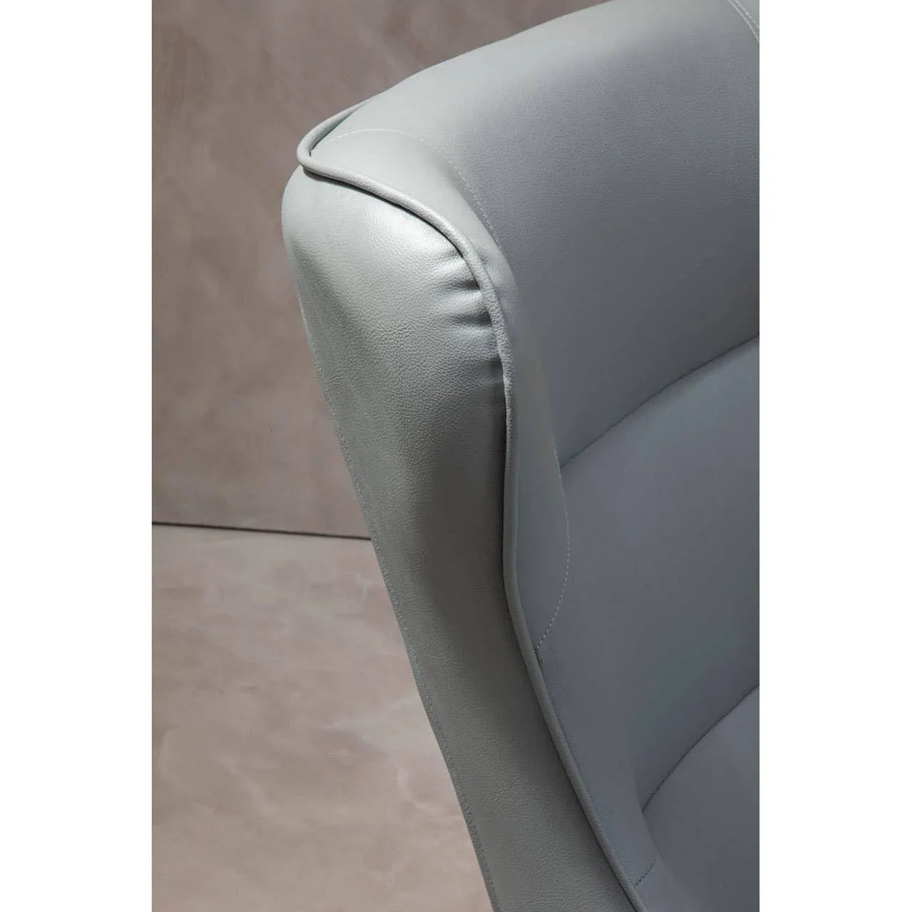Closeup of grey leather armchair backrest with curved detail and stitched seam
