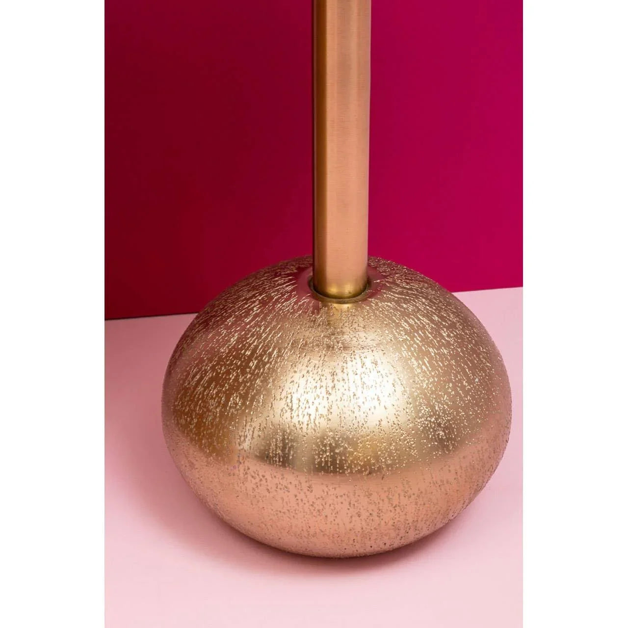 Gold textured lamp base with metallic finish against pink background