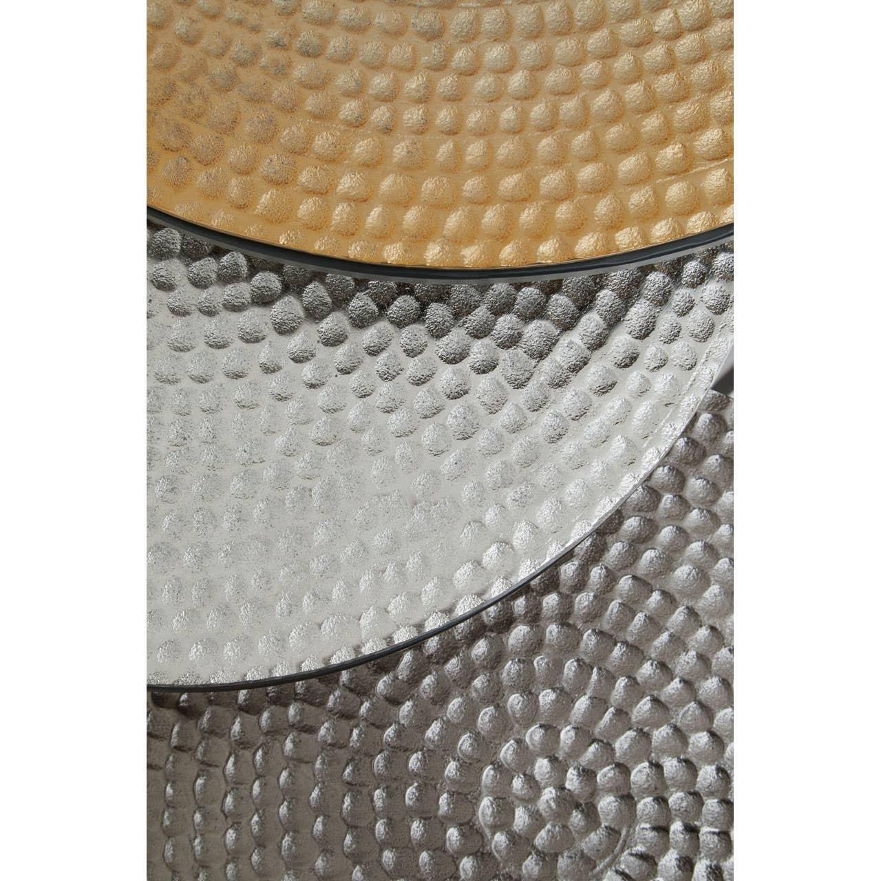 Close detail of nested metallic coffee table tops with hammered texture in gold and silver finish