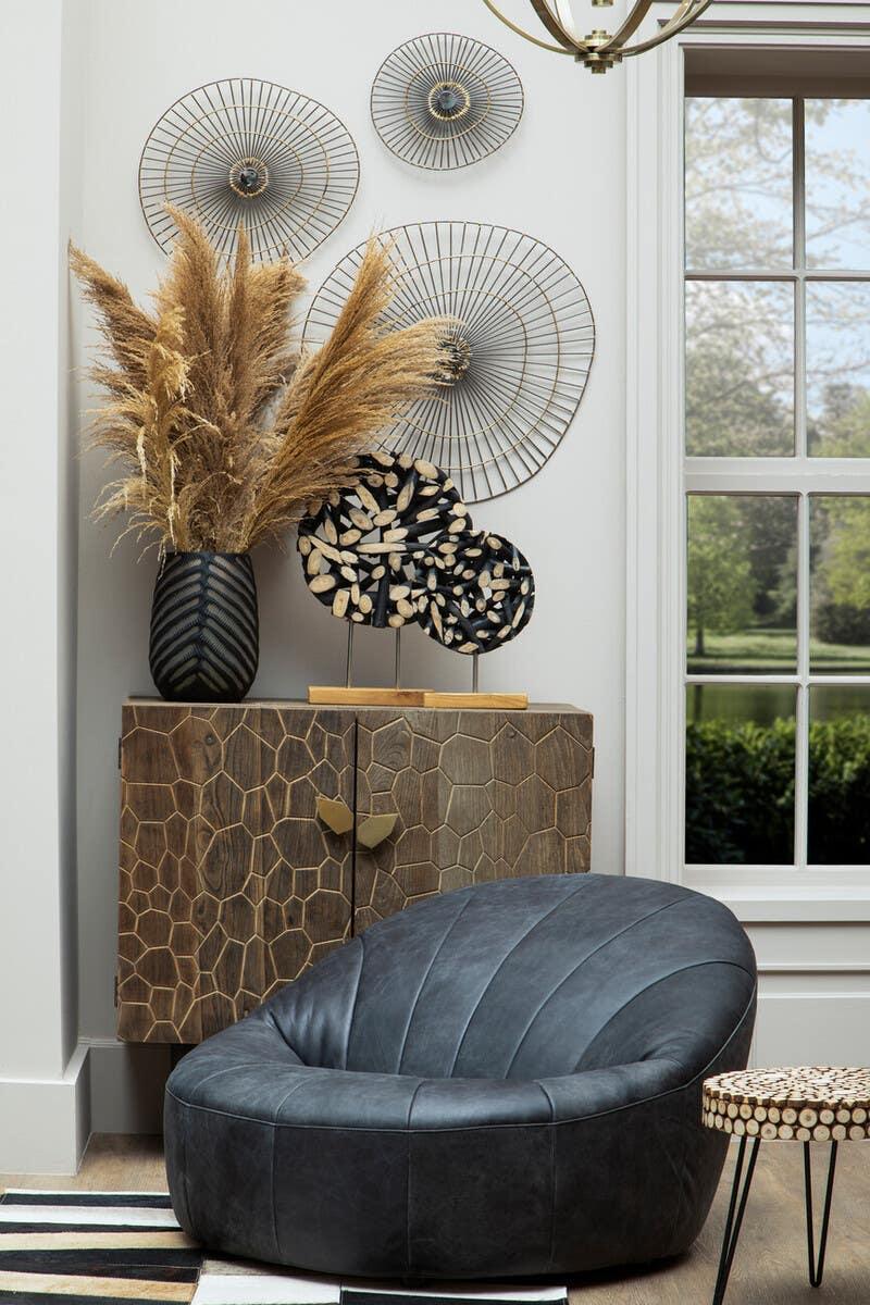 Modern black leather accent chair with geometric wooden cabinet and wall decor in living room