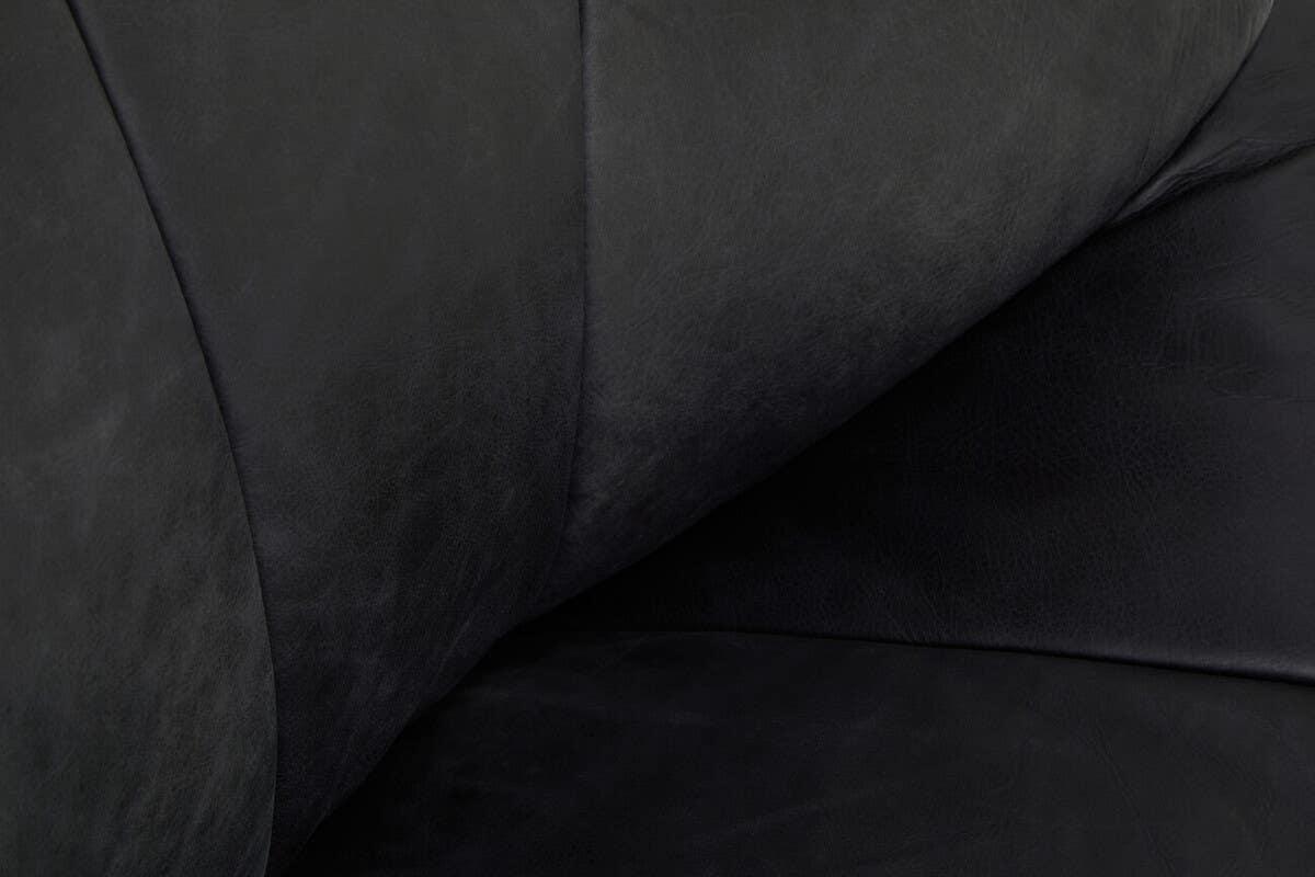 Closeup of black leather sofa cushions with visible grain texture and stitching detail