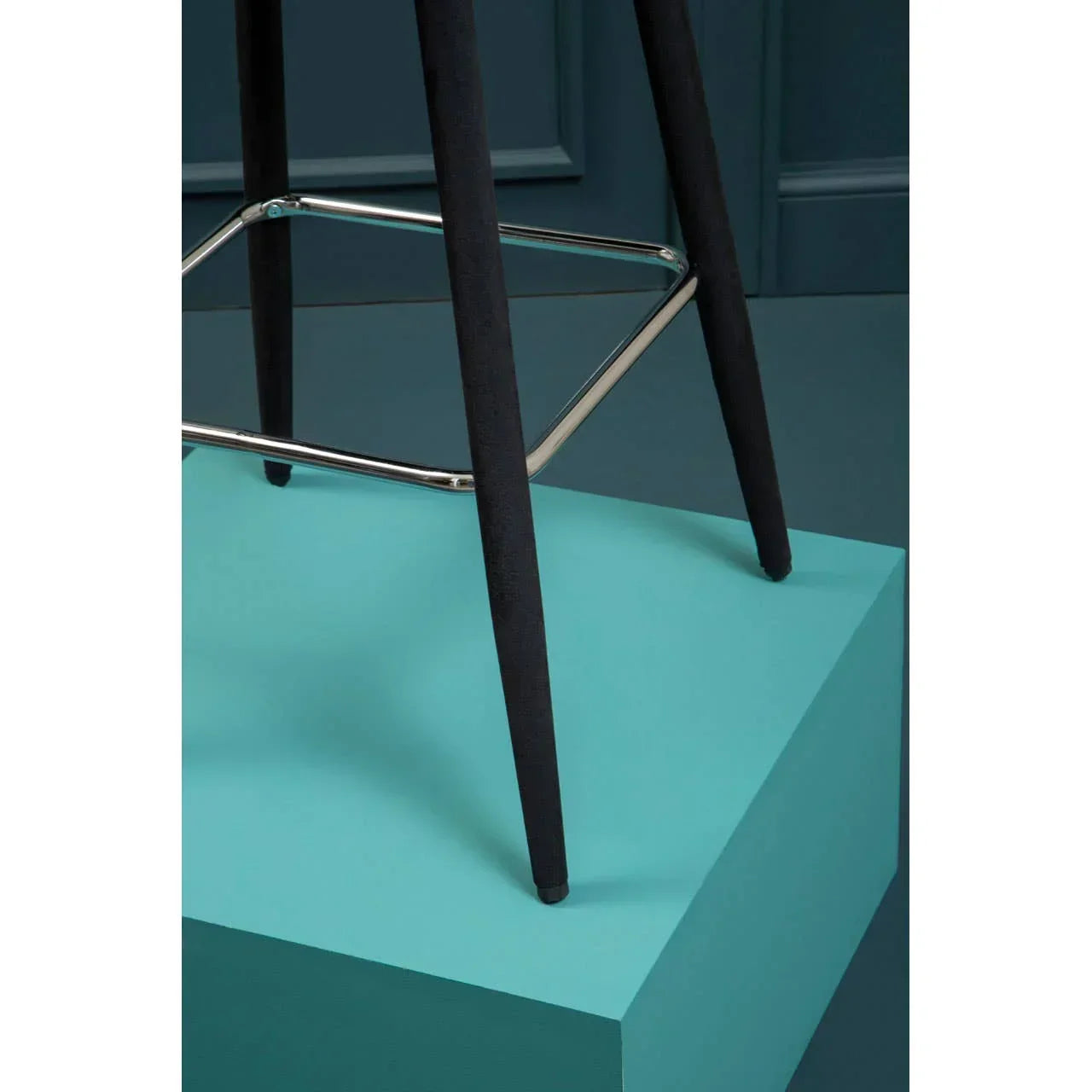 Black bar stool legs with chrome footrest on blue pedestal